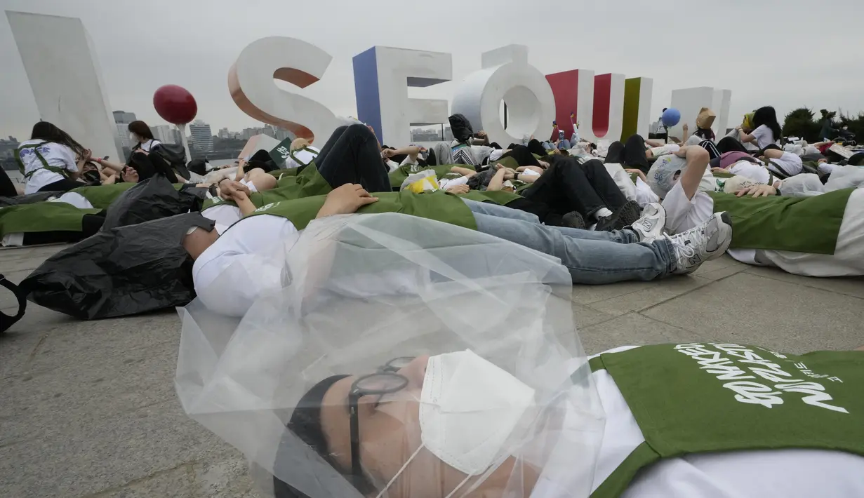 <p>Aktivis lingkungan mengenakan pakaian yang terbuat dari sampah plastik berbaring di tanah selama kampanye untuk memperingati Hari Bumi melawan perubahan iklim di Seoul, Korea Selatan, Jumat (22/4/2022). (AP Photo/Ahn Young-joon)</p>