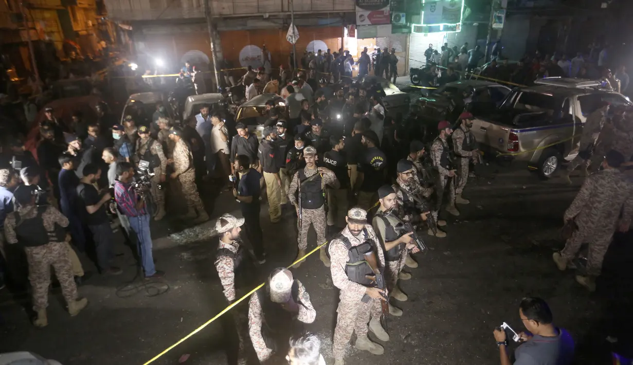 Pejabat keamanan Pakistan berkumpul di lokasi ledakan bom, di Karachi, Pakistan pada 12 Mei 2022. Sebuah bom pinggir jalan menargetkan sebuah van yang membawa pasukan keamanan Pakistan di kota pelabuhan selatan Karachi pada hari Kamis, menewaskan dan melukai beberapa orang, kata polisi. (AP Photo/Fareed Khan)