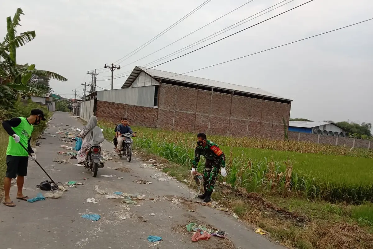 Serka Mashudi dan warga membersihkan sampah yang dibuang di tengah jalan raya, Rabu 19/5/2021. (Foto: Liputan6.com/Kusfitria Marstyasih)