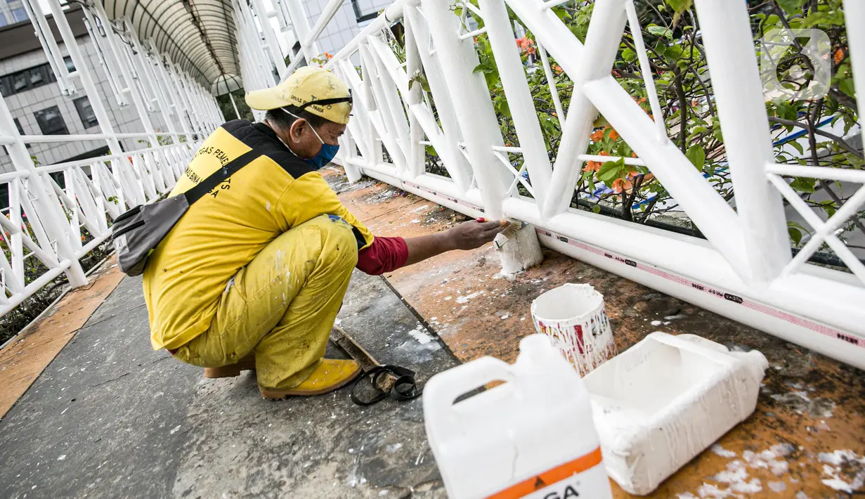 Pekerja Dinas Bina Marga DKI melakukan pengecatan ulang di sejumlah bagian dari Jembatan Penyeberangan Orang (JPO) di kawasan Thamrin, Jakarta, Kamis (28/1/2021). Pengecatan ulang itu sebagai bagian dari perawatan JPO di Jakarta guna memberikan kesan bersih dan indah. (Liputan6.com/Faizal Fanani)
