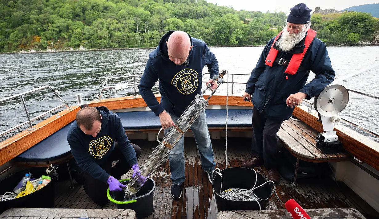 Ahli genetika Universitas Otago Profesor Neil Gemmell (tengah) mengambil sampel air dari perairan Loch Ness, Drumnadrochit, Skotlandia, 11 Juni 2018. Ini merupakan studi terbesar yang pernah dilakukan pada wilayah air tawar terbesar di Inggris itu. (Andy Buchanan/AFP)
