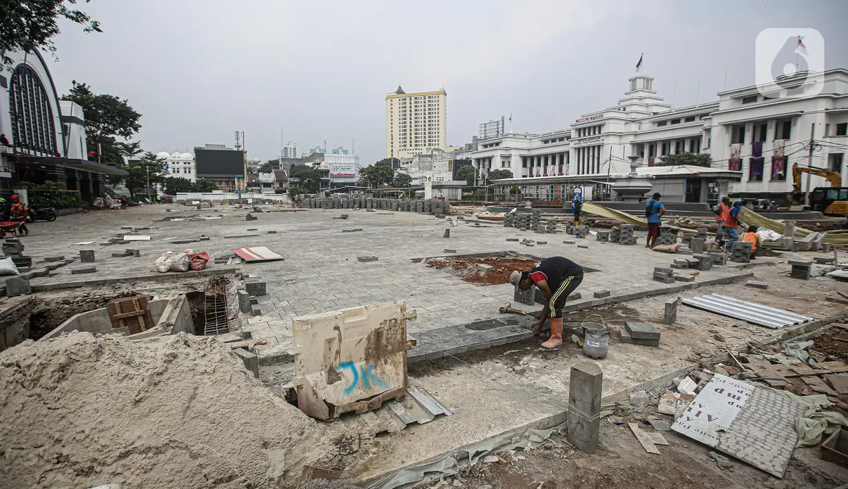 Pekerja menyelesaikan proyek revitalisasi di depan Stasiun Jakarta Kota, kawasan Kota Tua, Jakarta, Sabtu (23/7/2022). Pemprov DKI Jakarta menyatakan program revitalisasi di kawasan Kota Tua salah satunya bertujuan untuk meningkatkan aksesibilitas dengan mengintegrasikan beragam moda transportasi seperti kereta api, MRT, Transjakarta hingga angkutan perkotaan. (Liputan6.com/Faizal Fanani)
