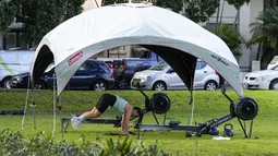 Seorang wanita berolahraga di sebuah taman di pinggiran timur Sydney, pada 14 September 2021. Pelatih kebugaran telah mengubah taman kawasan tepi laut di Rushcutters Bay Sydney menjadi gym luar ruangan untuk menyiasati pembatasan lockdown karena pandemi covid-19. (AP/Mark Baker)