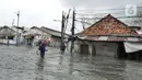 Seorang pria memanggul sepeda melewati banjir rob di kawasan Pelabuhan Sunda Kelapa, Jakarta, Selasa (7/12/2021). Banjir rob setinggi satu meter memutus Jalan Kerapu yang menghubungkan Ancol-Pluit. (merdeka.com/Arie Basuki)
