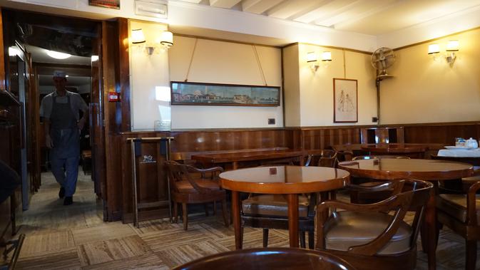 Interior Harry's Bar sangat minimalis.dengan perabotan yang terdiri dari meja dan bangku kayu. Dindingnya dihiasi lukisan bertema keindahan Venesia. (Liputan6.com/Marco Tampubolon)