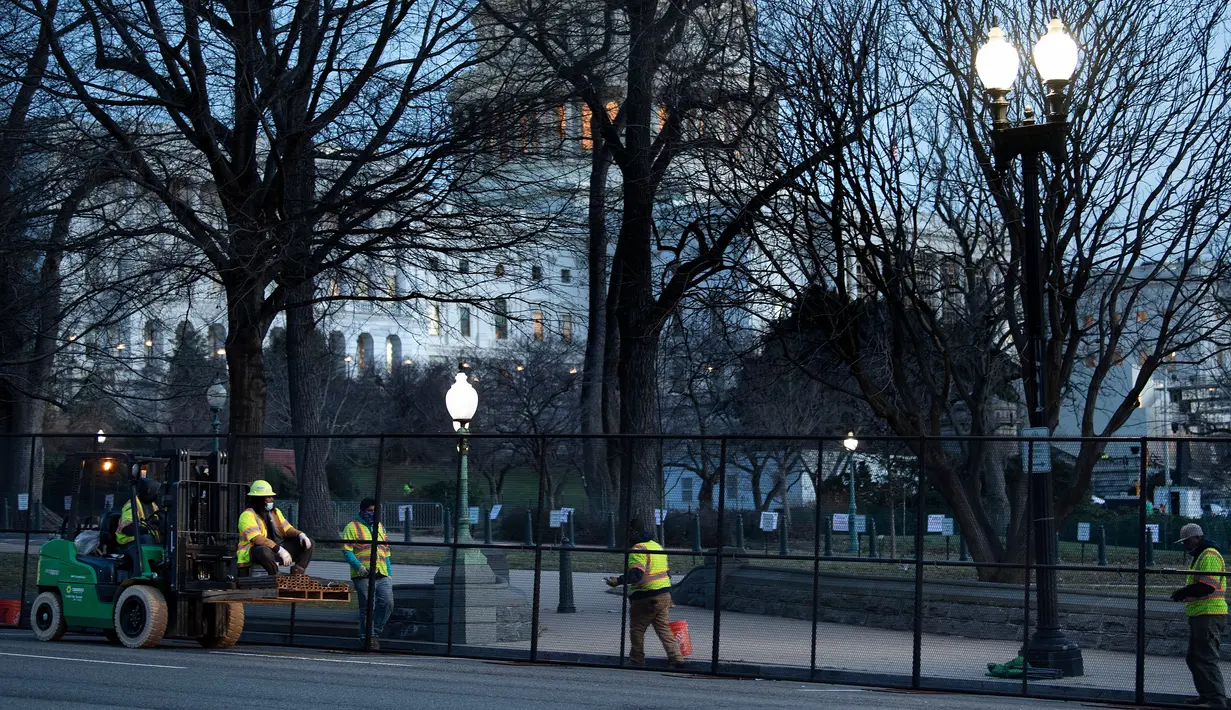 Pekerja memasang pagar pengendali kerumunan di sekitar Capitol Hill sehari setelah massa pendukung Donald Trump menerobos masuk ke Gedung Capitol, Washington, DC. Kamis (7/1/2021). Serangan dilakukan saat para anggota Kongres hendak mengesahkan kemenangan Joe Biden. (Brendan Smialowski/AFP)
