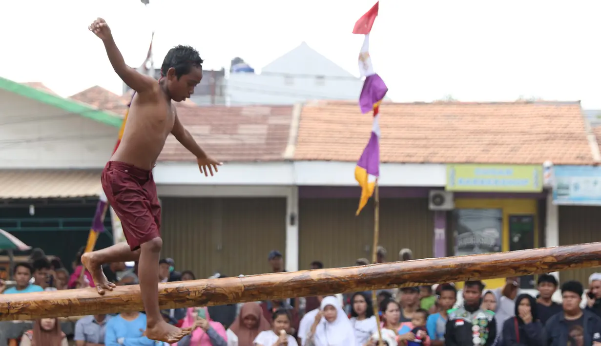 Anak-anak bermain lomba jalan di atas batang pohon pinang di sekitar Kalimalang, Jakarta, Sabtu (17/8/2019). Beragam lomba permainan digelar warga untuk menyemarakkan HUT ke-74 Republik Indonesia. (Liputan6.com/Helmi Fithriansyah)