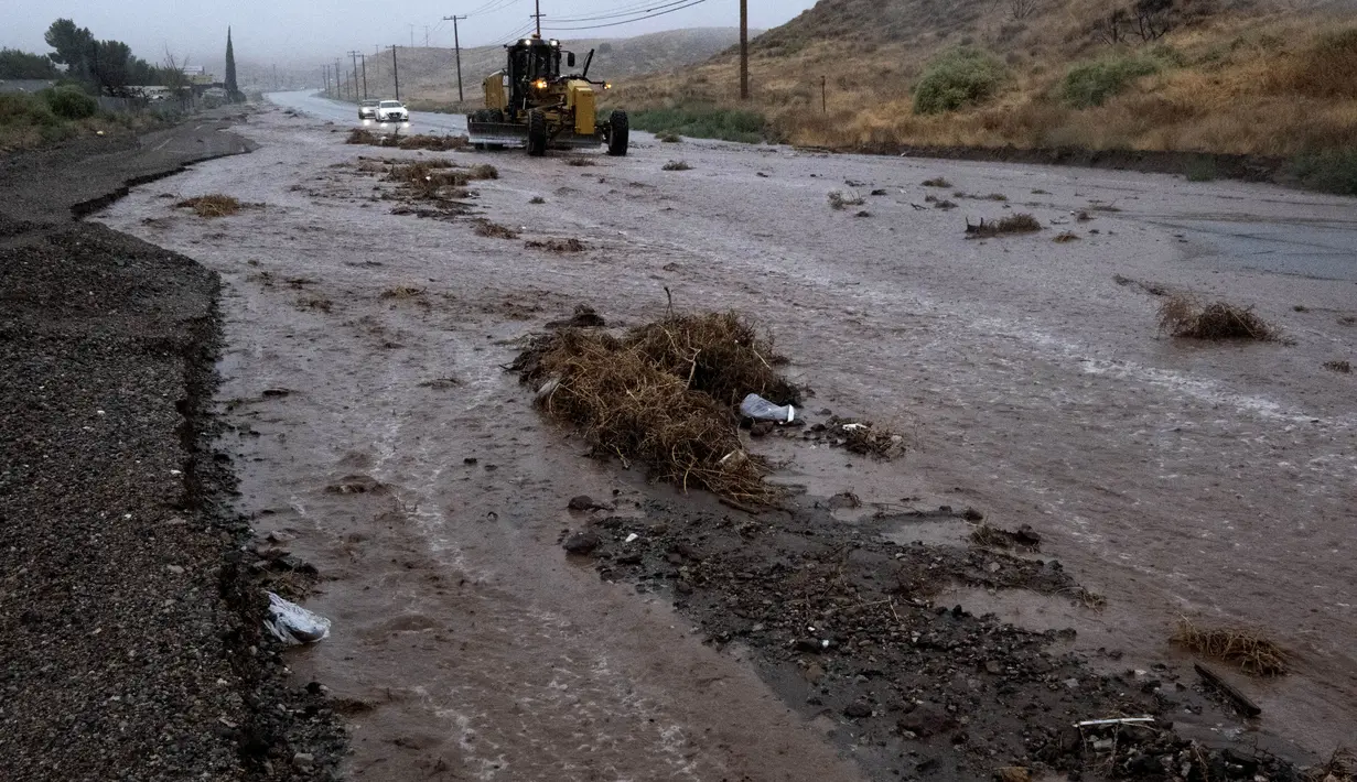 Kendaraan Bajak membersihkan puing-puing di sepanjang Sierra Highway yang banjir di Palmdale, California, saat Badai Tropis Hilary bergerak melalui area tersebut pada Minggu, 20 Agustus 2023. (AP Photo/Richard Vogel)