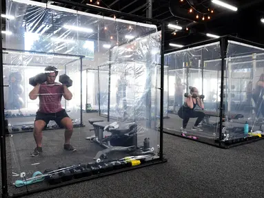 Orang-orang berolahraga dalam kotak plastik yang disediakan oleh Inspire South Bay Fitness di Redondo Beach, California pada 15 Juni 2020. Ruangan gym dengan plastik sebagai pemisah itu agar pengunjung dapat tetap berolahraga sambil tetap menjaga jarak fisik. (FREDERIC J. BROWN / AFP)