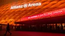 Seorang pria melintasi Allianz Arena, markas FC Bayern Munchen, yang diterangi warna oranye untuk kampanye "Orange the World" di Munich, Jerman, Senin (25/11/2019). Cahaya berwarna oranye untuk melambangkan partisipasi mendukung penghapusan kekerasan terhadap perempuan. (Lino Mirgeler/dpa/AFP)