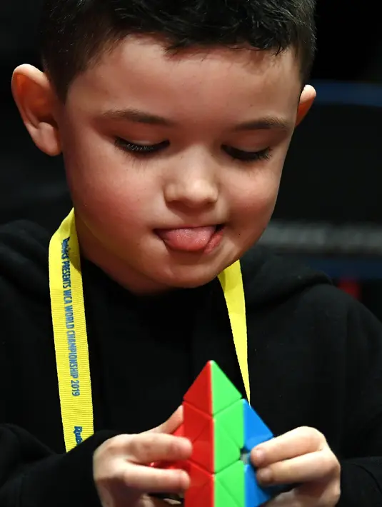 Seorang anak laki-laki serius memecahkan permainan rubik pada kejuaraan kubus Rubik Dunia di Melbourne, Australia (12/7/2019). Permainan Kubus Rubik 3x3x3, ditemukan oleh Profesor Rubik dari Hongaria pada tahun 1974. (AFP Photo/William West)