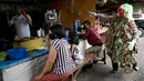 Polisi mengenakan topeng menyeramkan yang disebut "Leak" saat sosialisasi langkah-langkah pencegahan COVID-19 di pasar tradisional di Kerobokan, Denpasar, Kamis (14/5/2020). Kegiatan itu untuk mengimbau masyarakat terus melakukan berbagai upaya pencegahan penyebaran COVID-19. (SONNY TUMBELAKA/AFP)