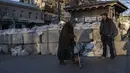 Seorang wanita lanjut usia berjalan melewati balok beton dengan karung pasir di sebuah jalan di Odesa, Ukraina selatan, pada Selasa, 22 Maret 2022. Perang Rusia yang tak henti-hentinya di Ukraina memaksa lebih banyak pengungsi untuk meninggalkan rumah mereka. (AP Photo/Petros Giannacouris)