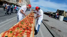 Sejumlah koki ahli berupaya mencetak rekor dunia dengan membuat pizza terpanjang di dunia, di sepanjang pinggir Laut Naples, Italia, 18 Mei 2016. Pizza itu memiliki ukuran sekitar 1 mil dan terbentang di sepanjang pinggir Laut Naples. (Mario LAPORTA/AFP)