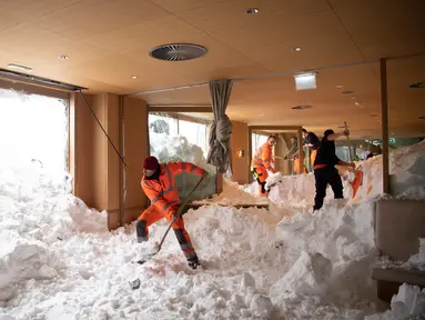 Petugas membersihkan longsoran salju yang masuk ke dalam Hotel Saentis di Schwaegalp, Swiss, Jumat (11/1). Longsoran salju nyaris mengubur Hotel Saentis. (Gian Ehrenzeller/Keystone via AP)