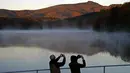 Pasangan mengambil foto saat matahari terbit di Price Lake sepanjang Blue Ridge Parkway dekat Blowing Rock, North California, saat musim gugur tiba, pada 19 Oktober 2021. (AP Photo/Gerry Broome)