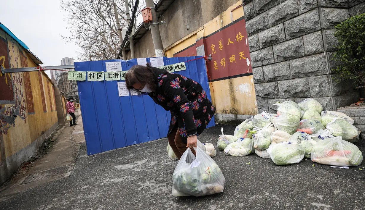 Seorang penduduk mengumpulkan makanan yang dibeli secara online di luar wilayah residen di Wuhan di provinsi Hubei tengah China (3/3/2020). otoritas kesehatan China melaporkan penurunan drastis untuk jumlah kasus-kasus baru di kota Wuhan dan di Provinsi Hubei dalam beberapa waktu terakhir. (AFP/STR)