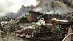 Pekerja dan petugas pemadam kebakaran mencoba memadamkan api di kapal nelayan di Pelabuhan Benoa, Denpasar, Bali, Senin (9/7). Kebakaran besar melalap 39 kapal yang tengah bersandar di dermaga. (SONNY TUMBELAKA/AFP)