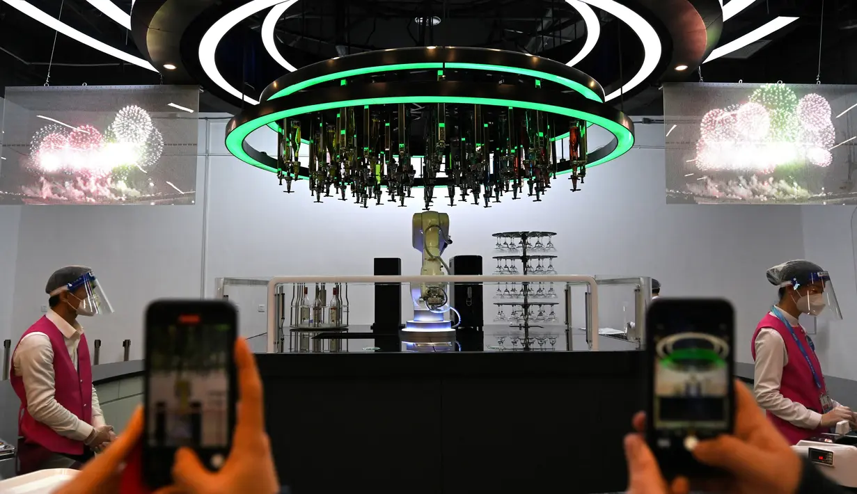 Sebuah robot membuat koktail di Pusat Media Utama Olimpiade Musim Dingin Beijing 2022 di Beijing pada 1 Februari 2022. Robotisasi layanan dibuat sebagai tindakan pencegahan terhadap virus corona Covid-19. (AFP/Gabriel Bouys)