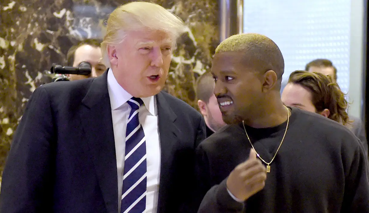 Presiden AS terpilih, Donald Trump dan Kanye West bebrincang sambil berjalan di lobi Trump Tower, New York, Selasa (13/12). Trump dan Kanye West melakukan pertemuan tertutup untuk membahas masalah multikultural. (TIMOTHY A. CLARY/AFP)