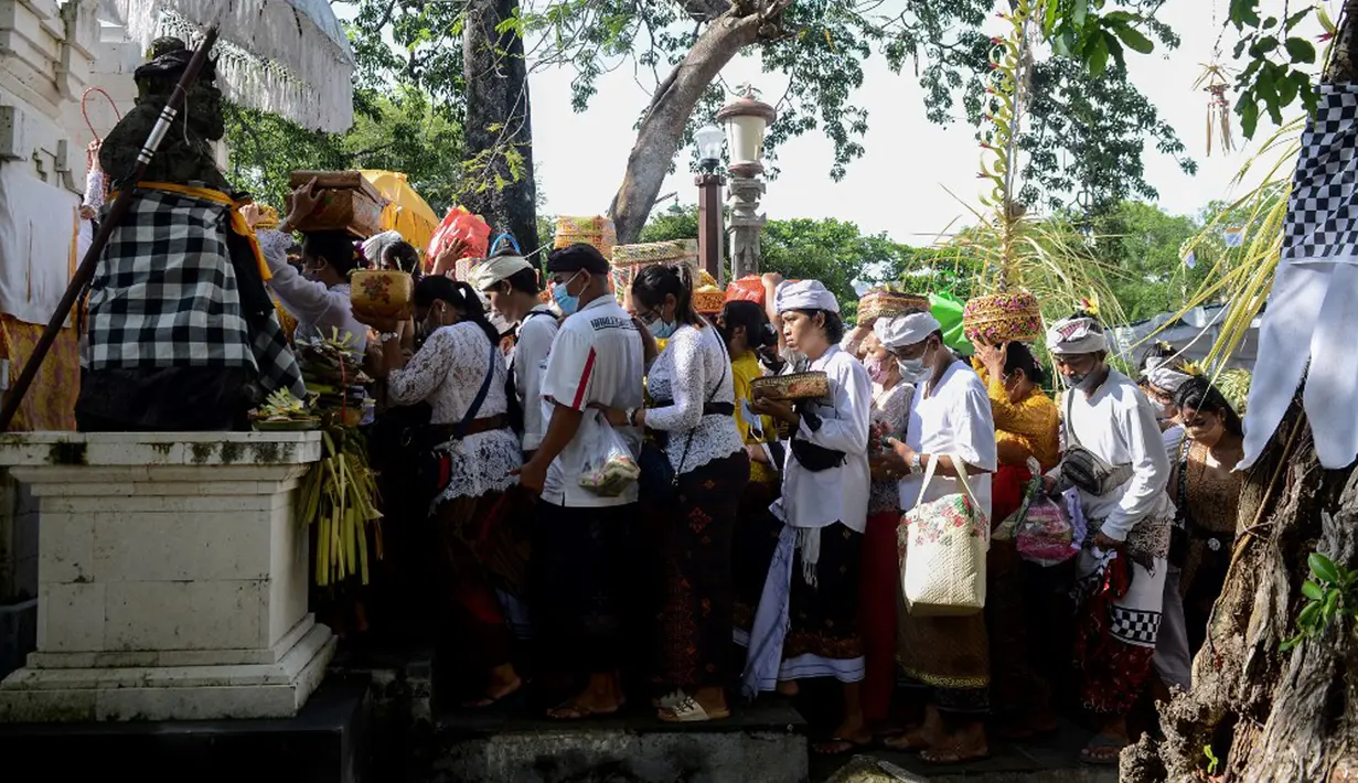 Umat Hindu membawa sesaji saat akan berdoa pada perayaan Hari Raya Kuningan di Pura Sakenan, Pulau Serangan, Denpasar, Bali, Sabtu (20/11/2021). Kuningan merupakan hari terakhir perayaan Galungan yang diyakini sebagai hari naiknya roh suci leluhur kembali ke surga. (Sonny TUMBELAKA/AFP)