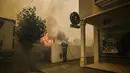 Seorang Pemadam Kebakaran berusaha memadamkan api di desa Cardigos di Macao, Portugal tengah (21/7/2019).  Kebakaran hutan tersebut memaksa penduduk desa dievakuasi ketempat yang lebih aman. (AFP Photo/Patricia De Melo Moreira)