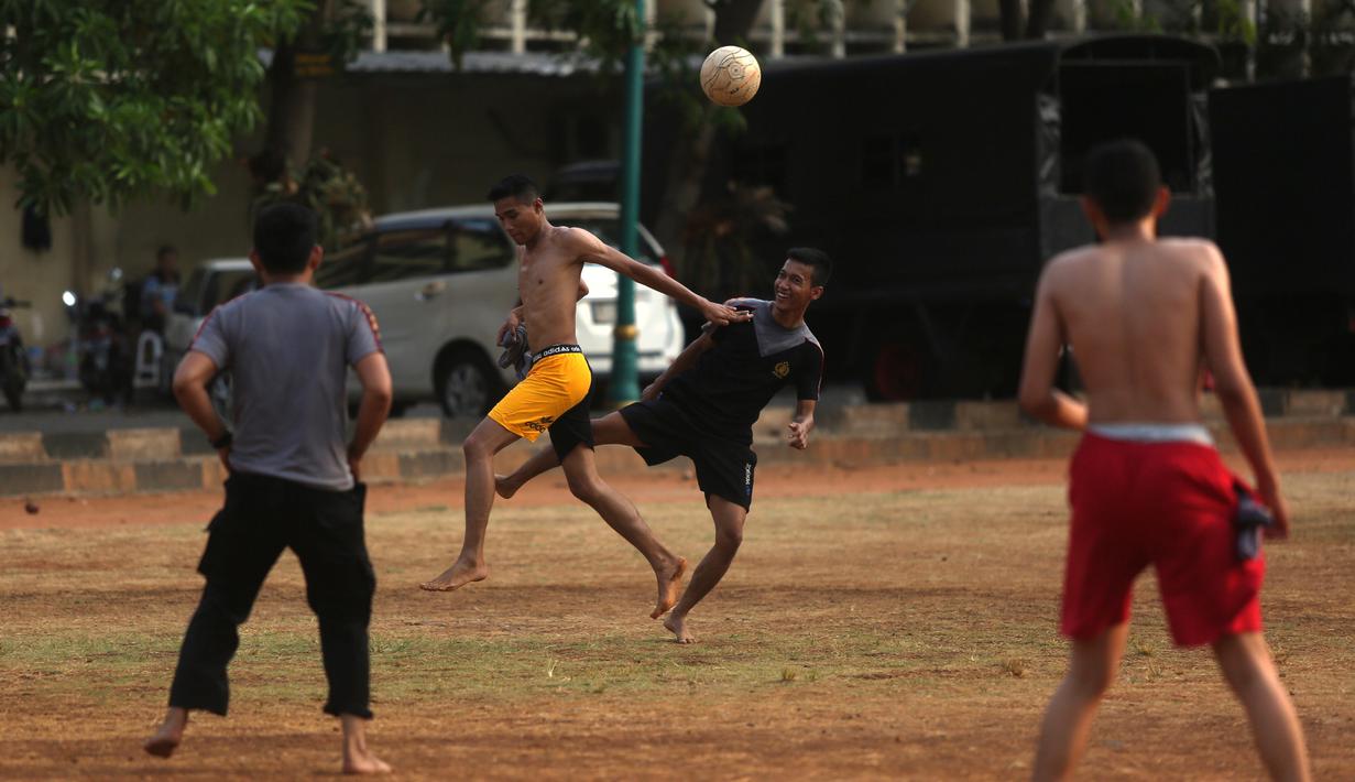 Polisi dari kesatuan Sabhara merenggangkan otot dengan bermain bola di Kawasan Polda Metro, Jakarta, Selasa (13/10/2015). Pihak Kepolisian dan TNI bersiap siaga menjelang laga Final Piala Presiden 2015. (Bola.com/Nicklas Hanoatubun).