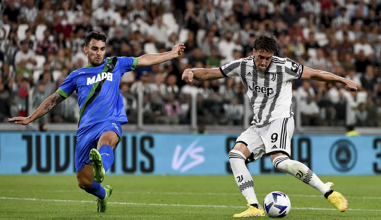 Penyerang Juventus, Dusan Vlahovic menembak bola dari kawalan pemain Sassuolo, Kaan Ayhan selama pertandingan pertandingan Liga Serie A Italia di stadion Juventus di Turin (15/8/2022). Juventus menang atas Sassuolo 3-0. (Marco Alpozzi/LaPresse via AP)