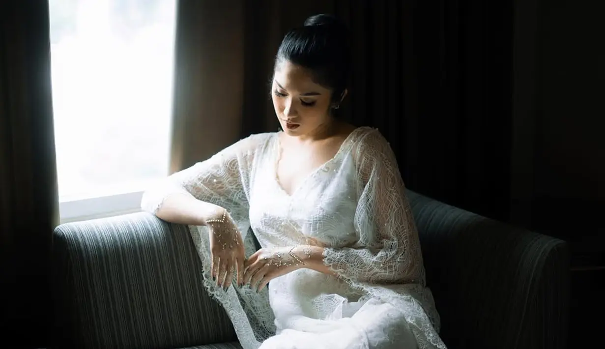 Bridal robe Ochi Rosdiana dilengkapi dengan renda halus dan detail bordiran yang semakin memperindah penampilannya. Dengan riasan natural dan tata rambut yang simpel namun elegan, ia terlihat begitu bersinar dalam setiap jepretan kamera. Pakaian ini tidak hanya melambangkan keanggunan, tetapi juga menggambarkan momen transisi menuju hari bahagia. (Liputan6.com/IG/@ochi24)