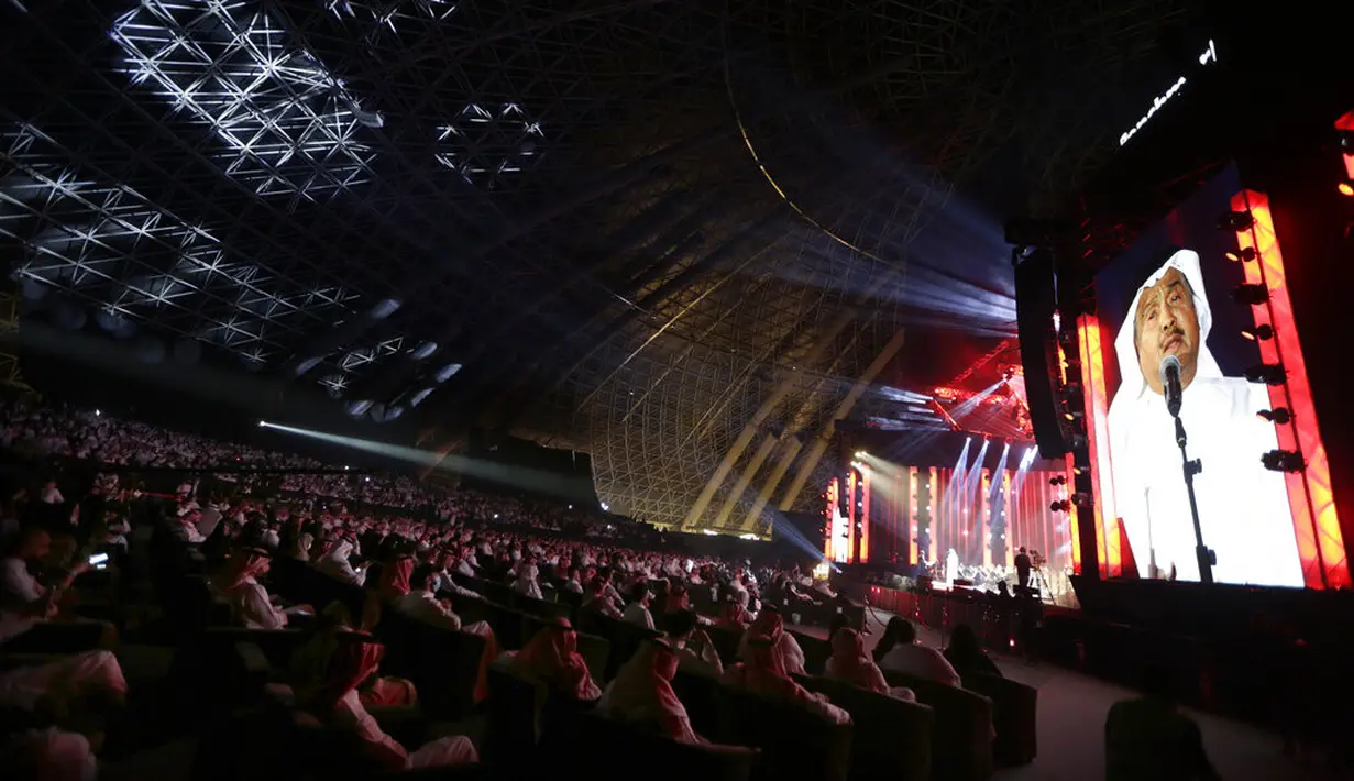 Penonton bersorak saat penyanyi terkemuka Saudi Mohammed Abdu, terlihat di layar, tampil di atas panggung di Super Dome yang baru dibangun, di Jeddah, Arab Saudi (8/7/2021). Konser ini diselenggarakan setelah kerajaan mencabut pembatasan virus corona pada acara di bulan Mei. (AP Photo/Amr Nabil)