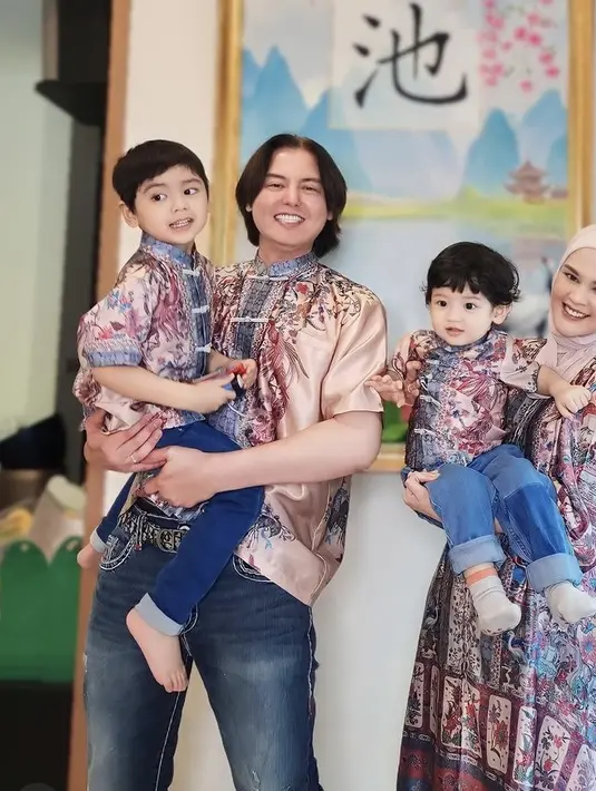 Foto ini diambil saat perayaan imlek, tetapi Sahabat Fimela bisa mencoba pose menggendong anak seperti yang dilakukan oleh Cut Meyriska dan Roger Danuarta dengan kedua anak tersayang mereka, untuk lebaran nanti. (Foto: Instagram/cutatumeyriska x @rogerojey x @cynthiatan_ x @claires.atelliers)