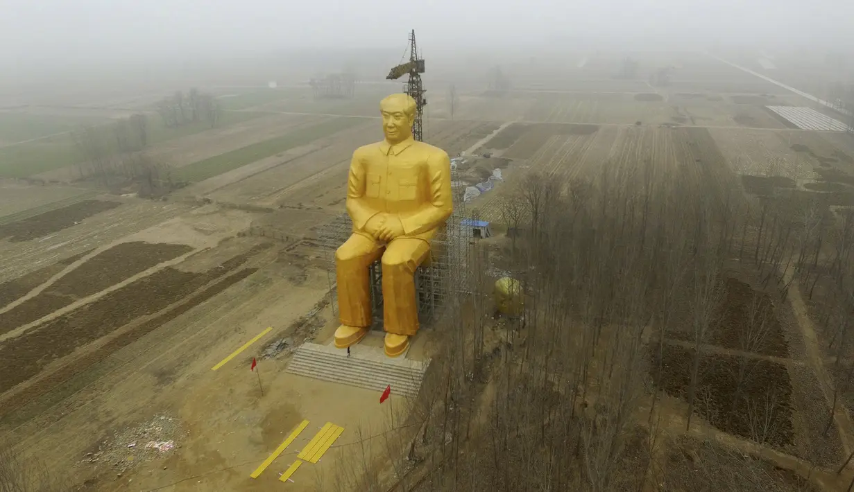 Sebuah Crane saat beroperasi di sebelah patung Presiden pertama Cina, Mao Zedong saat proses penyelesaian pembangunannya di ladang Desa Tongxu, Henan, Cina (4/1). Patung ini memiliki tinggi 36,6 meter dan dilapisi cat emas. (Reuters/Stringer)
