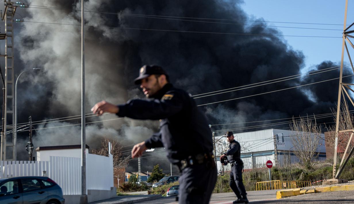Petugas mengatur lalu lintas di sekitar perusahaan kimia Indukern yang sedang terjadi kebakaran di kawasan industri Fuente del Jarro, Paterna, Valencia, Spanyol, Rabu (8/2). (AFP PHOTO / Biel Alino)