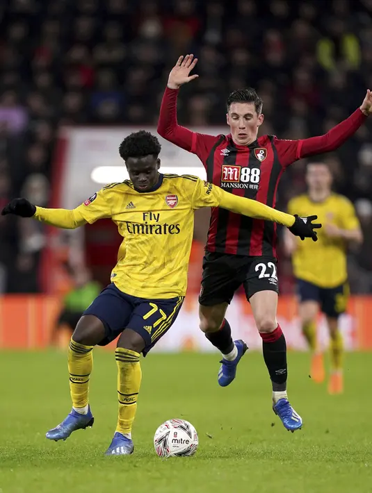Penyerang Arsenal, Bukayo Saka menggiring bola dari kawalan pemain Bournemouth, Harry Wilson pada pertandingan putaran keempat Piala FA di Stadion Vitalitas di Bournemouth, Inggris (27/1/2020).  Arsenal menang tipis 2-1 atas Bournemouth. (John Walton/PA via AP)