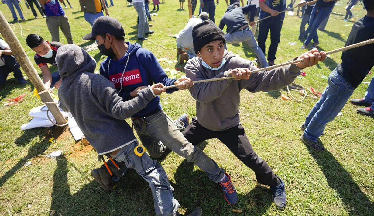 Warga membantu mengangkat layang-layang raksasa untuk ditampilkan pada Hari Semua Orang Kudus sebagai bagian dari perayaan Hari Kematian di Santiago Sacatepequez, Guatemala, 1 November 2021. Perayaan digelar dengan sejumlah pembatasan untuk mengekang penyebaran COVID-19. (AP Photo/Moises Castillo)