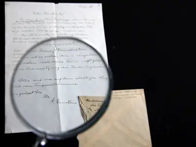 Petugas rumah lelang Winner melihat surat yang ditulis tangan Albert Einstein mengenai rumusan "Tahap Ketiga Teori Relativitas" dengan kaca pembesar di Yerusalem, Selasa (6/3). Surat itu dibeli dengan harga sekitar Rp 1,2 miliar. (MENAHEM KAHANA/AFP)