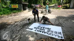 Warga memasang spaduk di jalan desa Glagahsari, Cangkringan Sleman yang di tanami sejumlah pohon, (23/2). Aksi penanaman pohon sebagai bentuk protes atas rusaknya jalan yang belum diperbaiki sejak 5 tahun letusan Merapi. (Liputan6.com/Boy Harjanto)