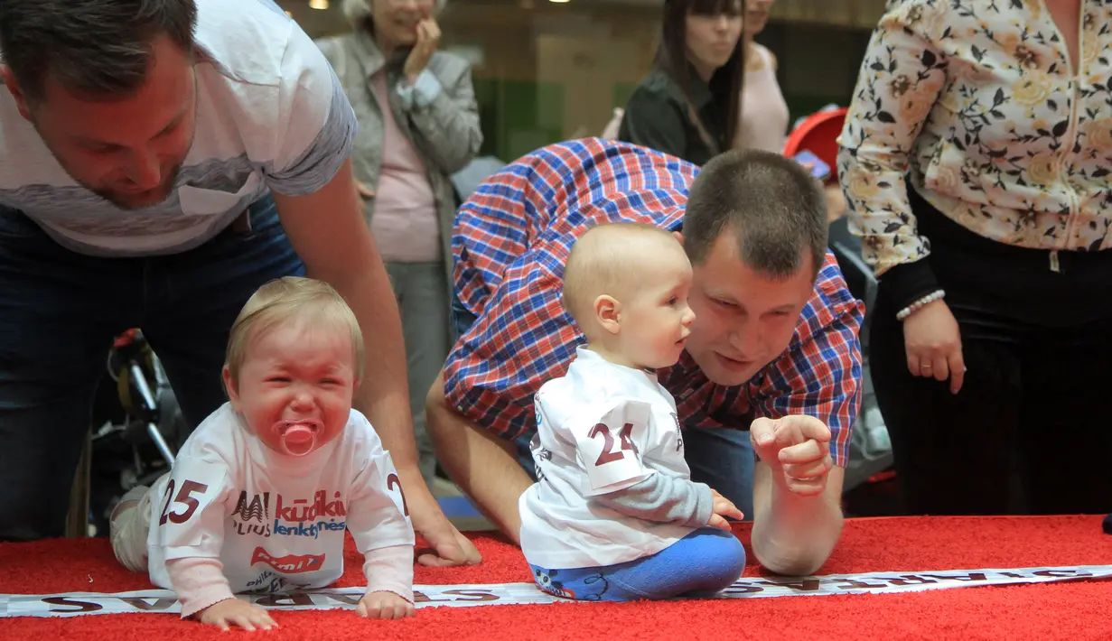 Sejumlah bayi bereaksi saat mengikuti lomba merangkak untuk memperingati Hari Anak Internasional di Vilnius, Lithuania, Kamis (1/6). Orang tua memberikan iming-iming benda kesukaan buah hatinya saat mengikuti lomba. (Petras Malukas/AFP)