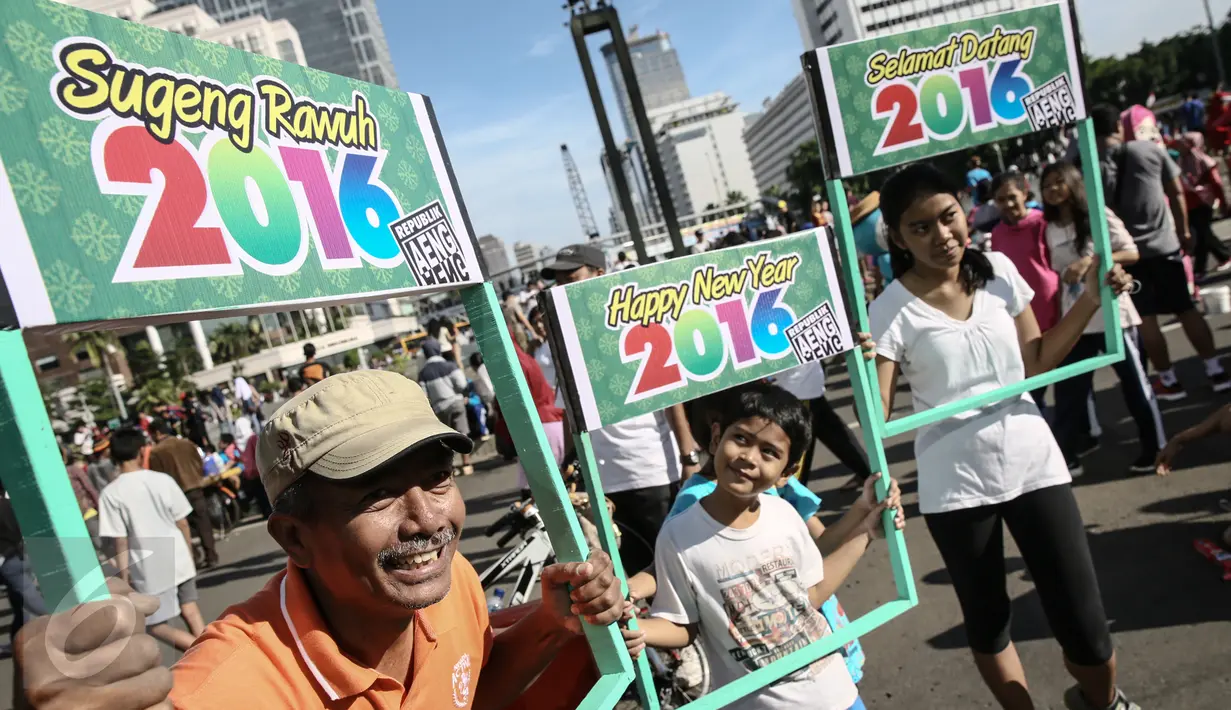 Sejumlah warga membawa papan bertulisan Happy New Year saat Car Free Day di sekitar Bunderan HI, Jakarta, Minggu (3/1/2016). Minggu pertama Tahun baru 2016 car free day ramai dipadati warga Jakarta. (Liputan6.com/Faizal Fanani)