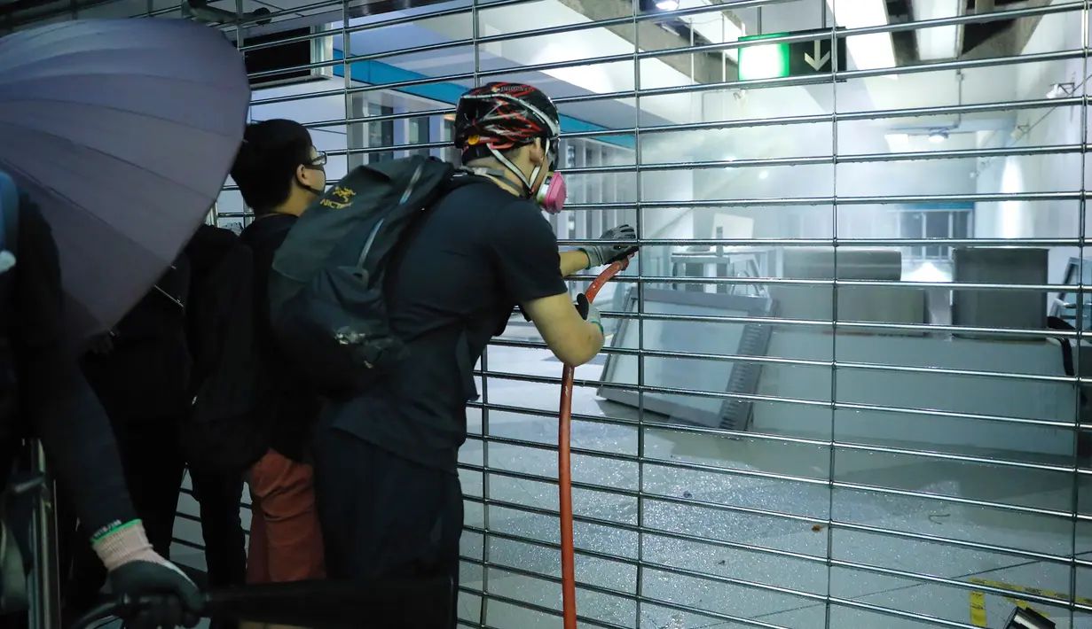 Demonstran menyemprotkan selang saat berunjuk rasa di Stasiun MTR Yuen Long, Hong Kong, Rabu (21/8/2019). Sejumlah demonstran yang menggunakan masker atau penutup wajah, bentrok dengan aparat kepolisian. (AP Photo/Kin Cheung)