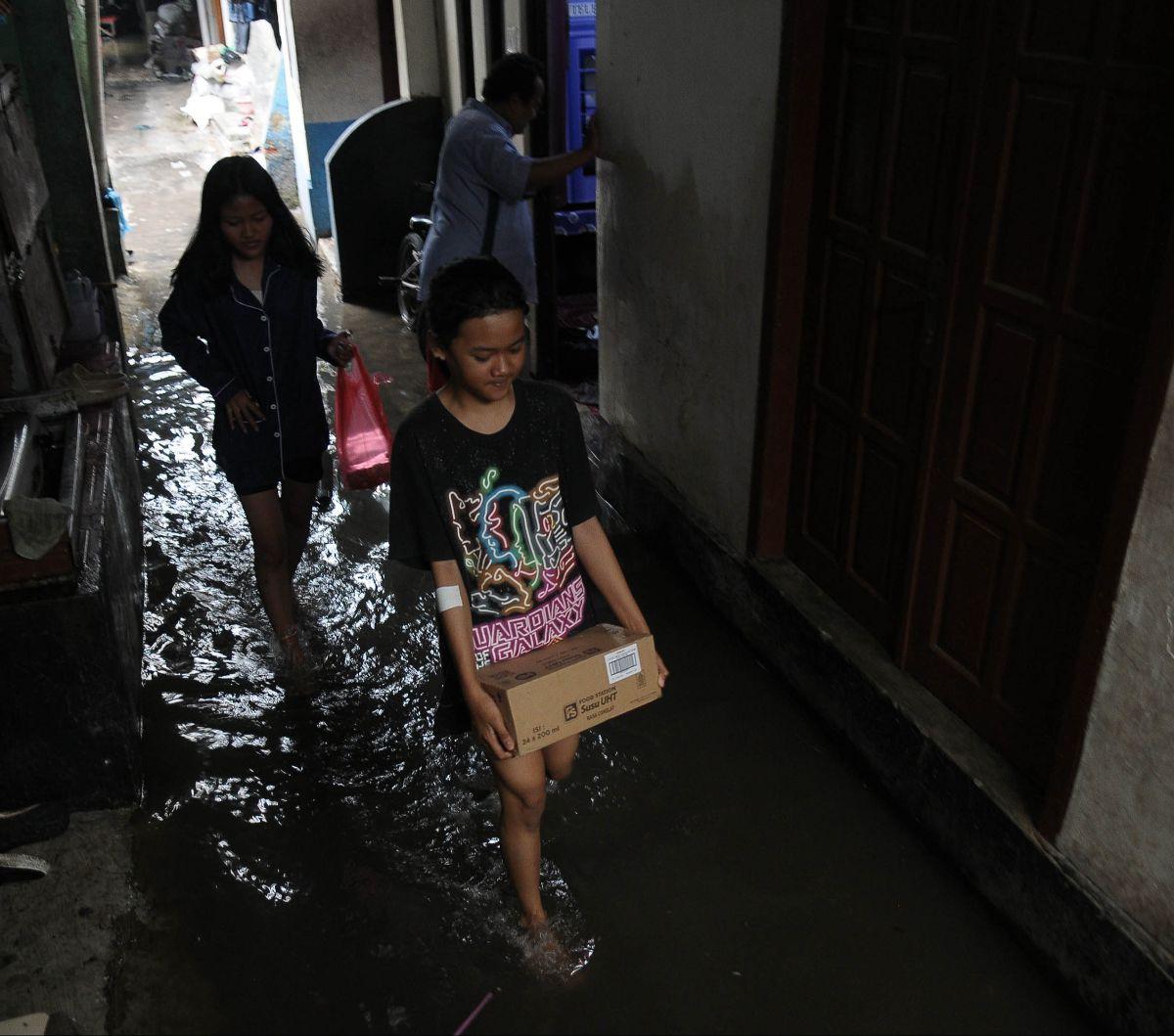 Warga beraktivitas di tengah banjir yang merendam lingkungan RT 16/04, Kelurahan Rawa Terate, Kecamatan Cakung, Jakarta Timur, Rabu (31/1/2024). Hujan yang mengguyur sejak malam  hari membuat pemukiman warga di Kelurahan Rawa Terate terendam banjir. Foto: