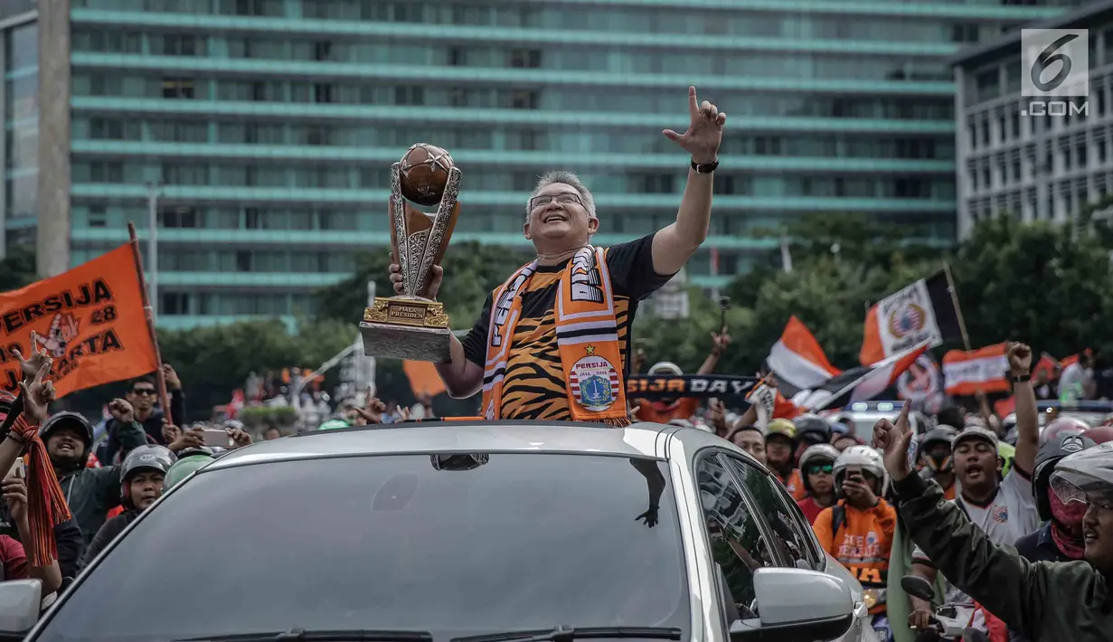 Ketua PP The Jakmania Ferry Indrasjarief membawa Piala Presiden yang diraih oleh Persija Jakarta pada pawai kemenangan di kawasan Sudirman, Minggu (18/2). Tak ada pengalihan arus di sepanjang jalur konvoi Persija dan Jakmania. (Liputan6.com/Faizal Fanani)