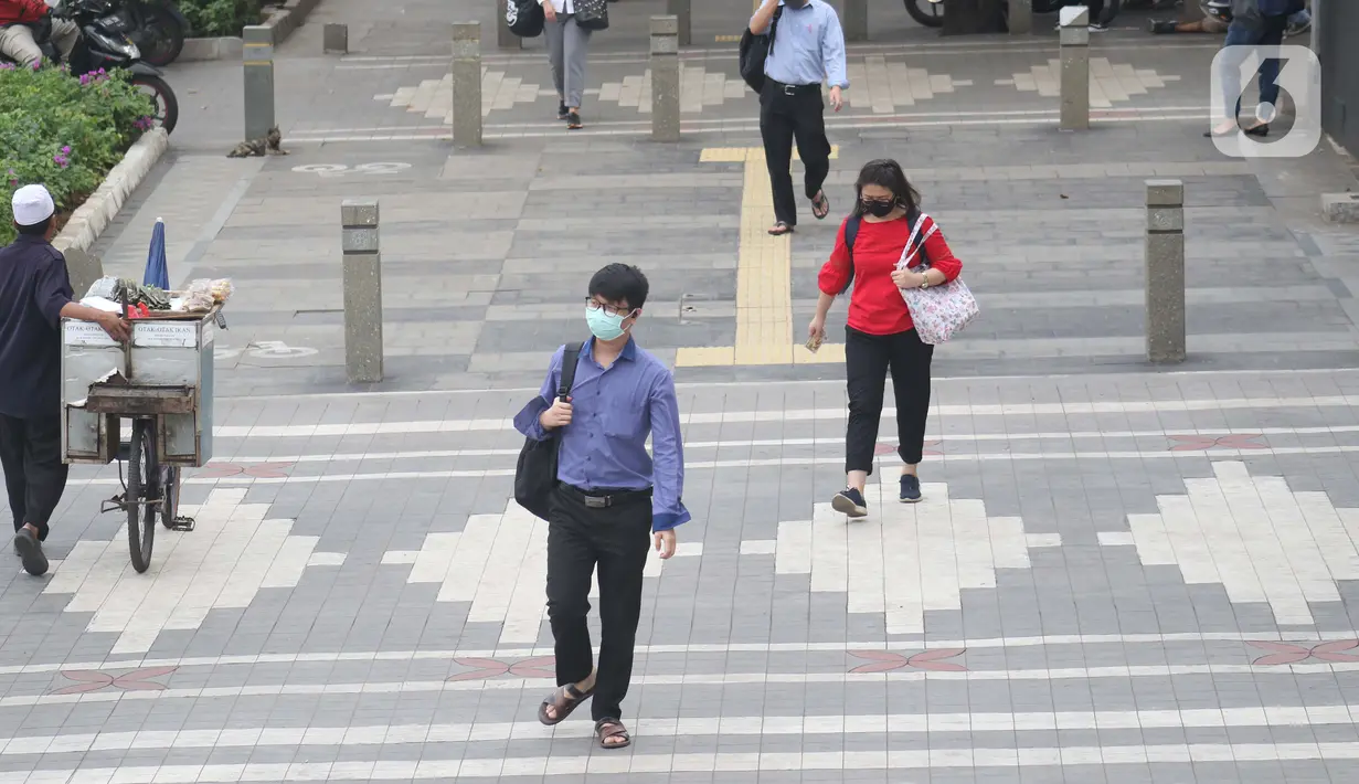 Warga mengenakan masker melintas di trotoar Jalan Jenderal Sudirman, Jakarta, Kamis (9/7/2020). Berdasar data yang diumumkan pemerintah pada Kamis (9/7) ada penambahan 2.657 orang yang terinfeksi COVID-19 sehingga jumlah penderita menjadi 70.736. (Liputan6.com/Helmi Fithriansyah)