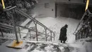 Seorang perempuan berjalan dengan hati-hati menuruni tangga ke stasiun kereta bawah tanah Columbus Circle saat badai salju melanda New York, Senin, (1/2/2021). Badai salju menyebabkan timbunan salju setinggi satu kaki di sepanjang wilayah pesisir timur AS, termasuk New York. (AP Photo/Wong Maye-E)