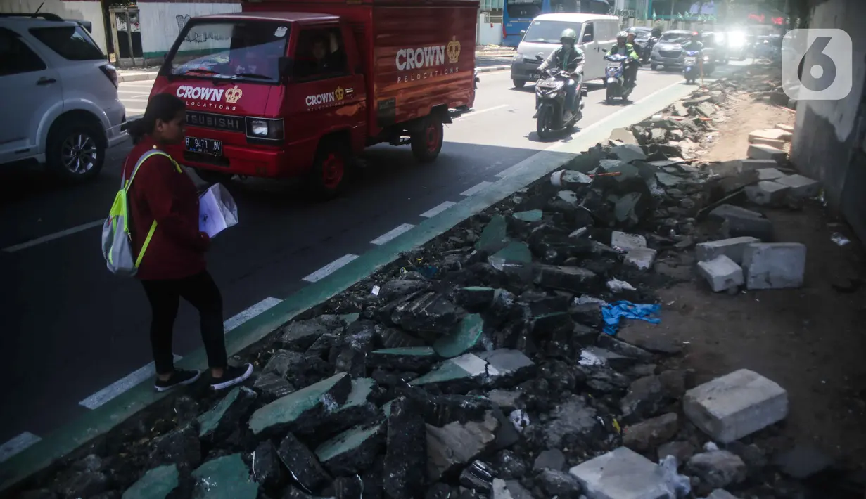 Pejalan kaki melintas di samping jalur sepeda yang di bongkar di kawasan Cikini, Jakarta, Selasa (19/11/2019). Jalur sepeda berumur 2 bulan tersebut dibongkar akibat proyek pelebaran trotoar. (Liputan6.com/Faizal Fanani)
