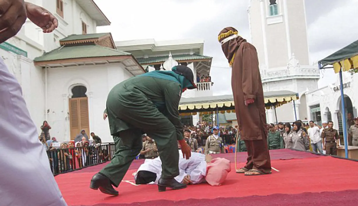 Petugas segera menolong Nur Elita, terpidana pelanggar hukum syariat, yang pingsan saat menjalani eksekusi hukuman cambuk di halaman Masjid Baiturrahim, Ulee Lheue, Banda Aceh, Senin (28/12).  (Jefta Images/dailymail.co.uk)