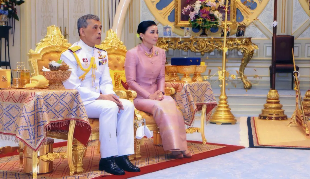 Raja Maha Vajiralongkorn (kiri) duduk bersama Ratu Suthida saat melangsungkan prosesi pernikahan mereka di Bangkok, Thailand, Rabu (1/5/2019). Ratu Suthida cukup lama menjadi pengawal pribadi Raja Maha Vajiralongkorn dan sering menghadiri acara publik bersama. (Thai TV Pool via Reuters)