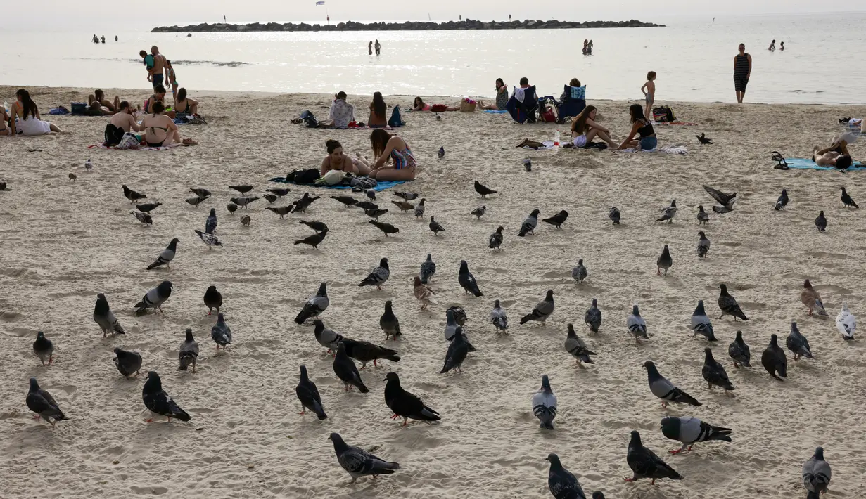 Orang-orang duduk di pantai di kota pesisir Israel Tel Aviv (19/4/2021). Dengan lebih dari setengah populasi divaksinasi penuh dalam salah satu kampanye inokulasi COVID-19 tercepat di dunia. (AFP/menahem kahana)