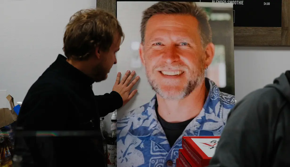 Jordan Hopkins menempatkan tangannya pada foto Sean Adler saat berkumpul untuk mengenang korban penembakan massal di bar California di Simi Valley, Thousand Oaks, Amerika Serikat, Kamis (8/11). (AP Photo/Jae C. Hong)