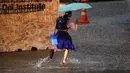 Seorang gadis sekolah berlari di jalan yang sebagian tergenang air saat hujan deras di Bangkok (23/9/2020). (AFP/Mladen Antonov)